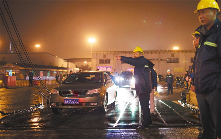 海口港16号码头，工作人员在雨中指挥滞留车辆登船过海